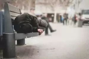 A homeless man is sleeping on bench